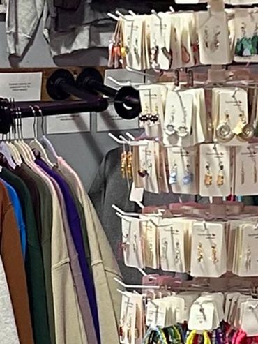 Clothing store with colorful sweatshirts and a neon sign.