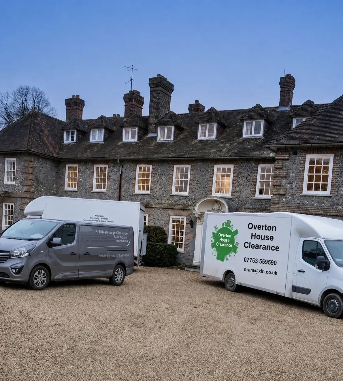 Two house clearance vans parked in front of a large old stone house.