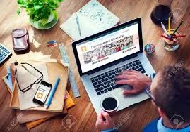 Person working on a laptop surrounded by office supplies and a cup of coffee.
