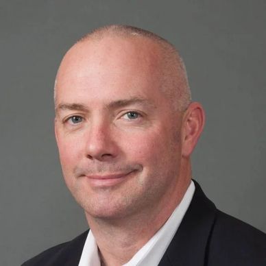 Portrait of a bald man in a suit jacket.