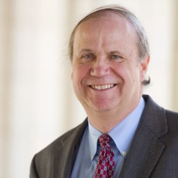 Smiling middle-aged man in a suit and patterned tie.