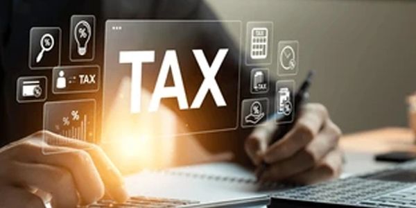 Person calculating taxes using a calculator and laptop.