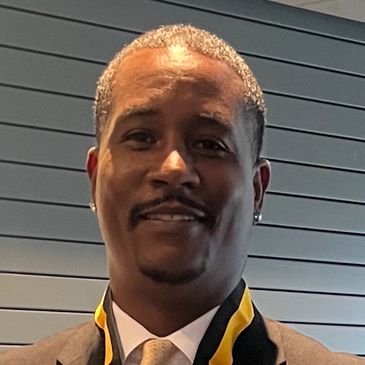 Man in suit smiling with a medal around his neck.