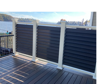 Modern deck railing with black horizontal panels and white posts overlooking a lake.