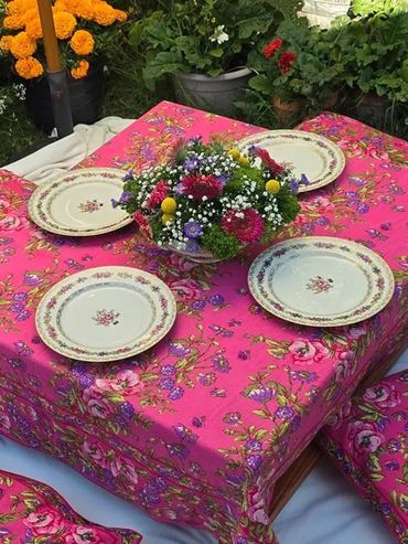 Outdoor table setting with floral tablecloth and vintage plates.