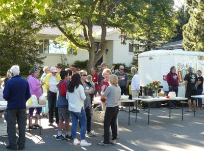People gathered outdoors near a trailer for an event.