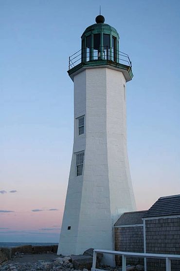 White lighthouse with green top against evening sky.