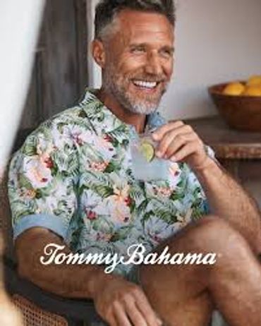 Smiling man in tropical shirt holding a drink.