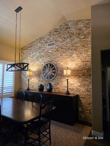 Rustic dining room with stone accent wall and elegant lighting.