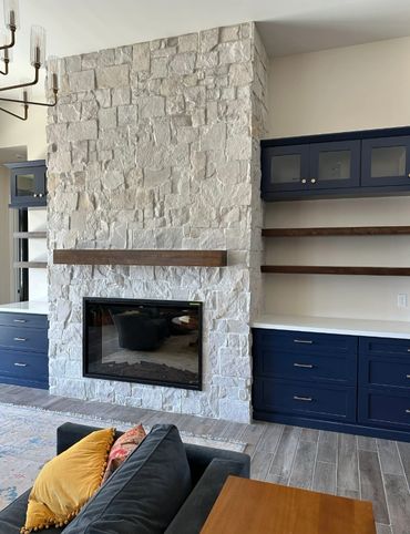 Modern living room with stone fireplace and navy cabinets.