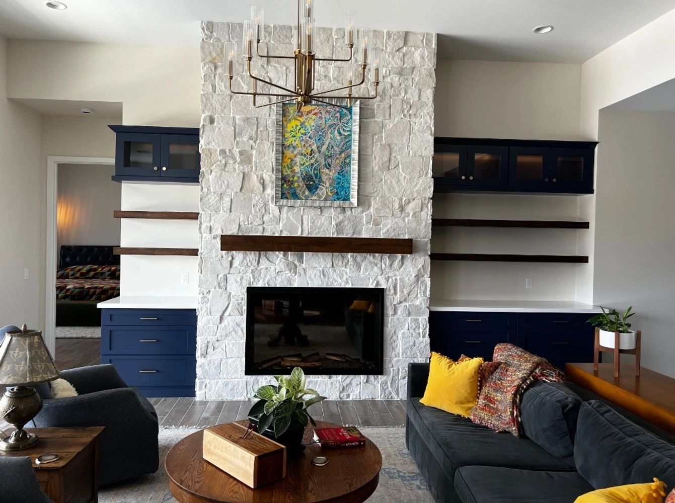 Modern living room with white stone fireplace and navy blue cabinets.