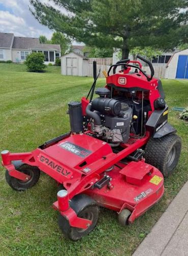 Red Gravely zero-turn lawn mower on a green lawn.