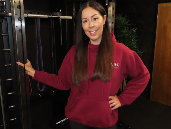 Woman in a red hoodie smiling at the gym.