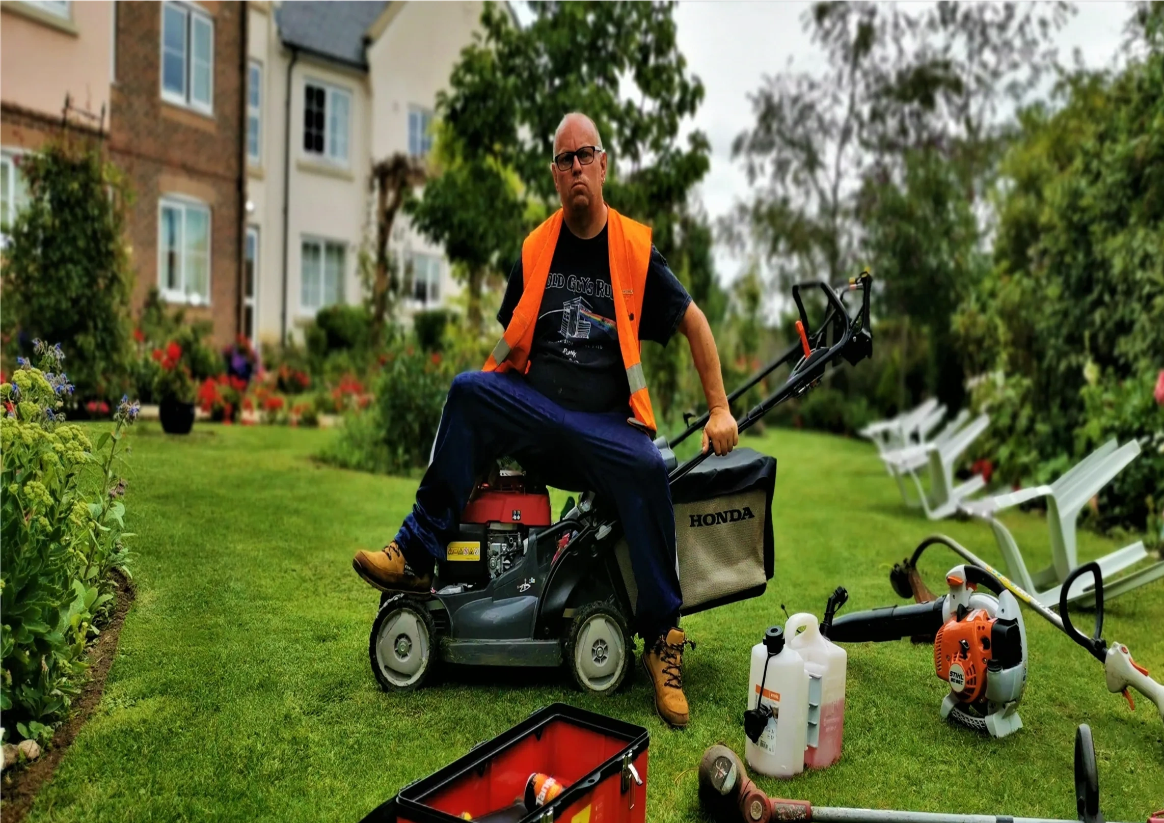 "Head gardener sitting on a lawnmower in a garden"