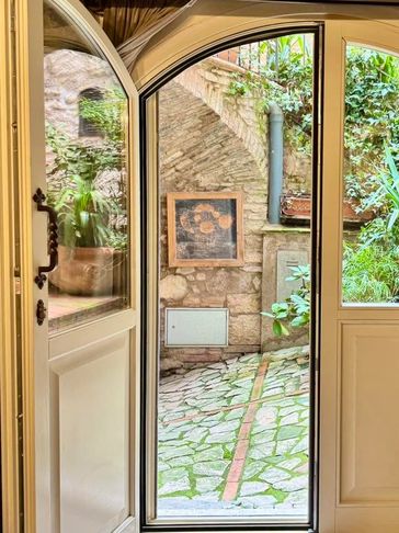 Open door revealing a rustic stone courtyard with greenery.