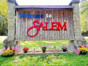 Welcome sign for Salem decorated with American flags and flowers.