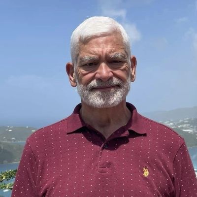 Smiling elderly man with white hair outdoors.