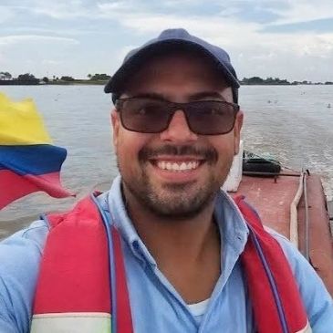 Hombre sonriente en un bote con bandera colombiana.
