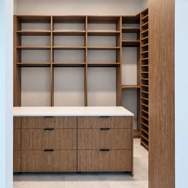 Modern wooden walk-in closet with empty shelves and drawers.