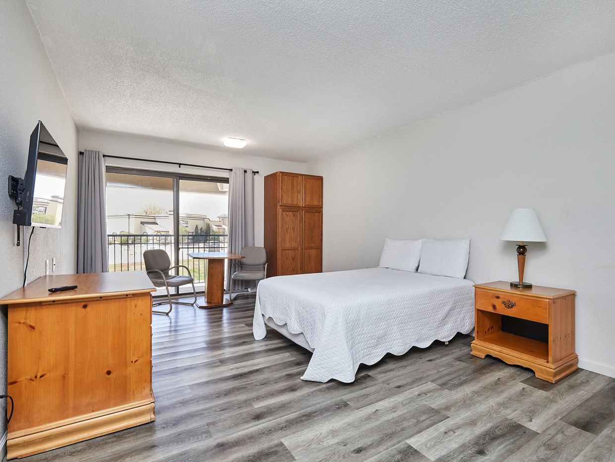Minimalist bedroom with wooden furniture and sliding glass door.
