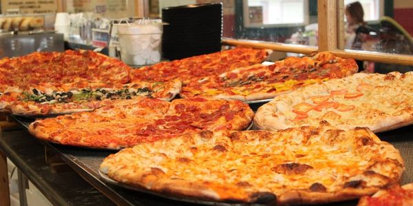 6 large pizzas on a counter ready to serve