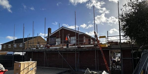 Construction workers on scaffolding at a building site under a blue sky.