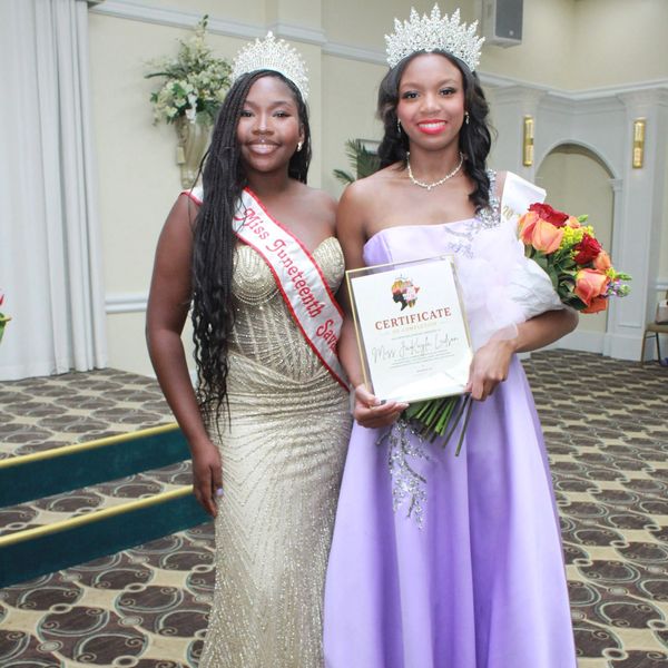 Two crowned women in elegant gowns at a pageant event.