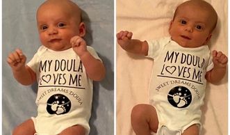 Two smiling babies wearing matching onesies that say 'My Doula Loves Me'.