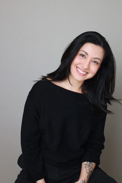 Smiling woman in black with a tattoo on her arm.