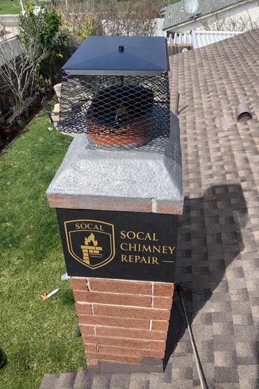A brick chimney with a black metal cap and a SoCal Chimney Repair sign.
