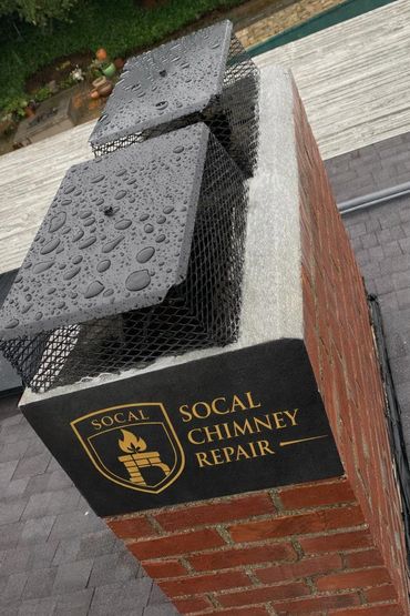 Rain-covered chimney caps on a brick chimney with a SoCal Chimney Repair sign.