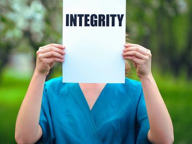 woman holding up a sign wit the word integrity on it to demonstrate our core value of honesty