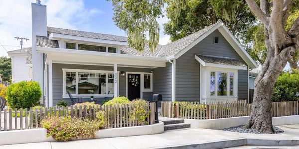 Gray house with white trim and wooden picket fence.