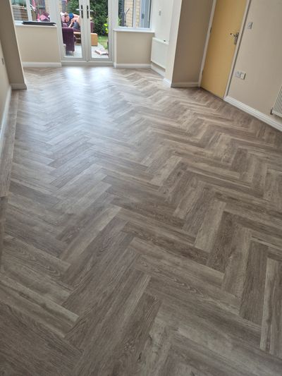 Newly installed herringbone patterned floor in an empty room with garden view.