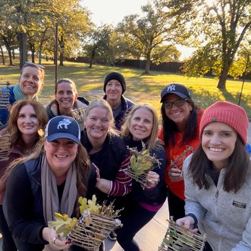 Group of smiling women outdoors holding crafts.