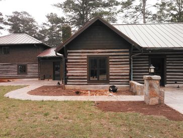 Log cabin-style house with fresh landscaping work, including dug-up soil