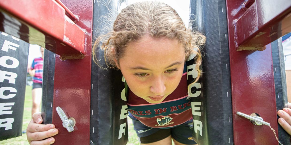 Girl practicing rugby tackling with a training machine.