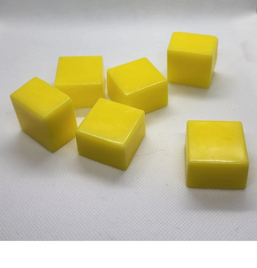 Six yellow wax cubes on a white surface.