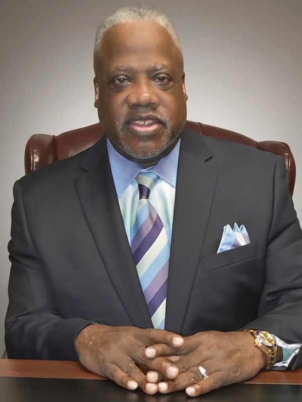 Man in suit sitting with hands folded.