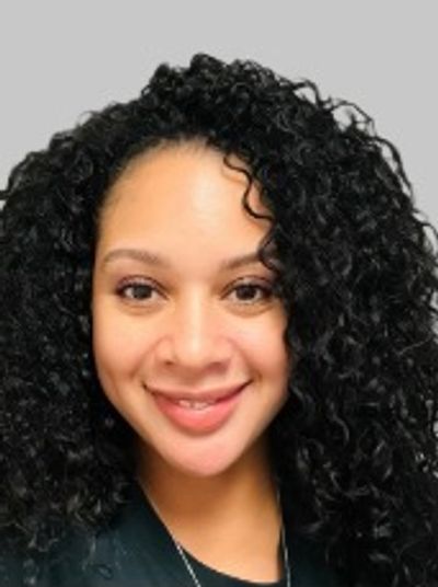 Smiling woman with curly black hair and warm eyes.