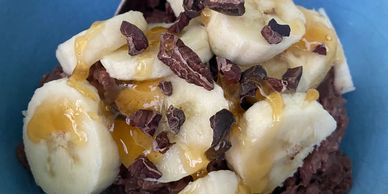 Chocolate porridge topped with banana, honey and cacao nibs. 