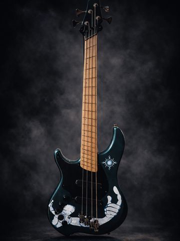 Black electric bass guitar with skeleton hand artwork and a sun design.