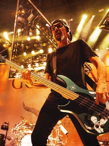 Musician playing bass guitar on stage with dramatic lighting.