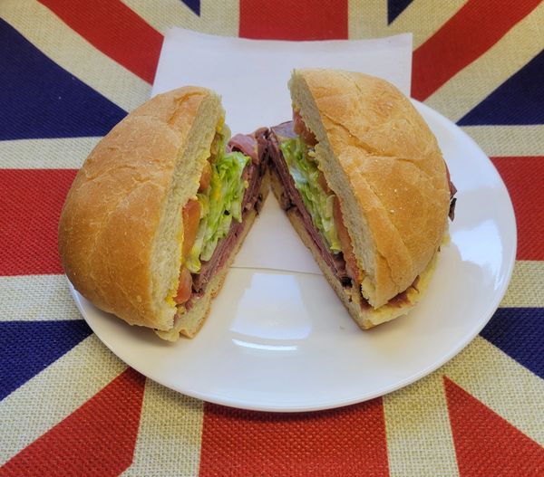 A sandwich cut in half on a white plate with a Union Jack tablecloth.