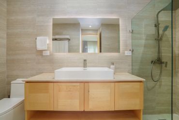 Modern bathroom with wooden vanity and glass shower.