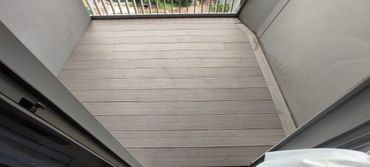 Empty balcony with wooden flooring and white railing.