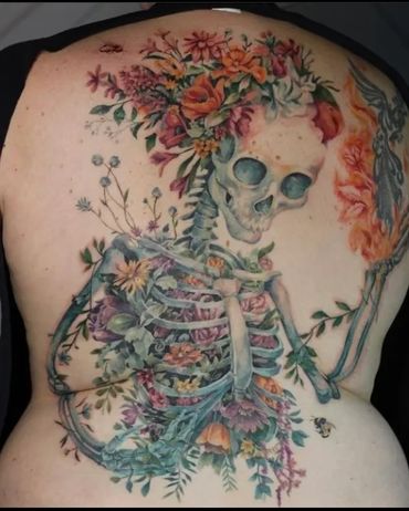 A stunning back piece of a skeleton with colour realism florals