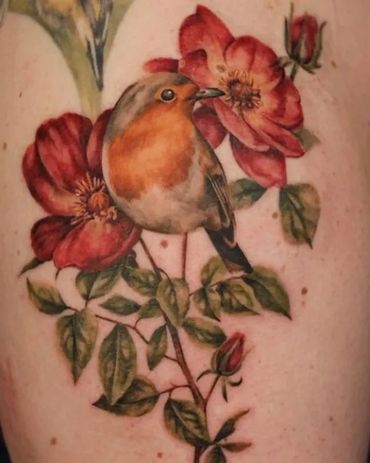 An amazing colour realism bird tattoo sitting on flowers
