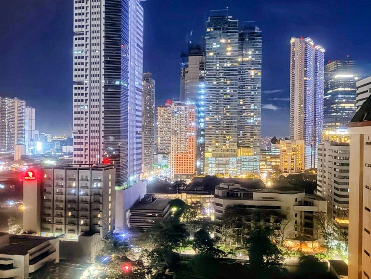Nighttime cityscape with illuminated skyscrapers and buildings.