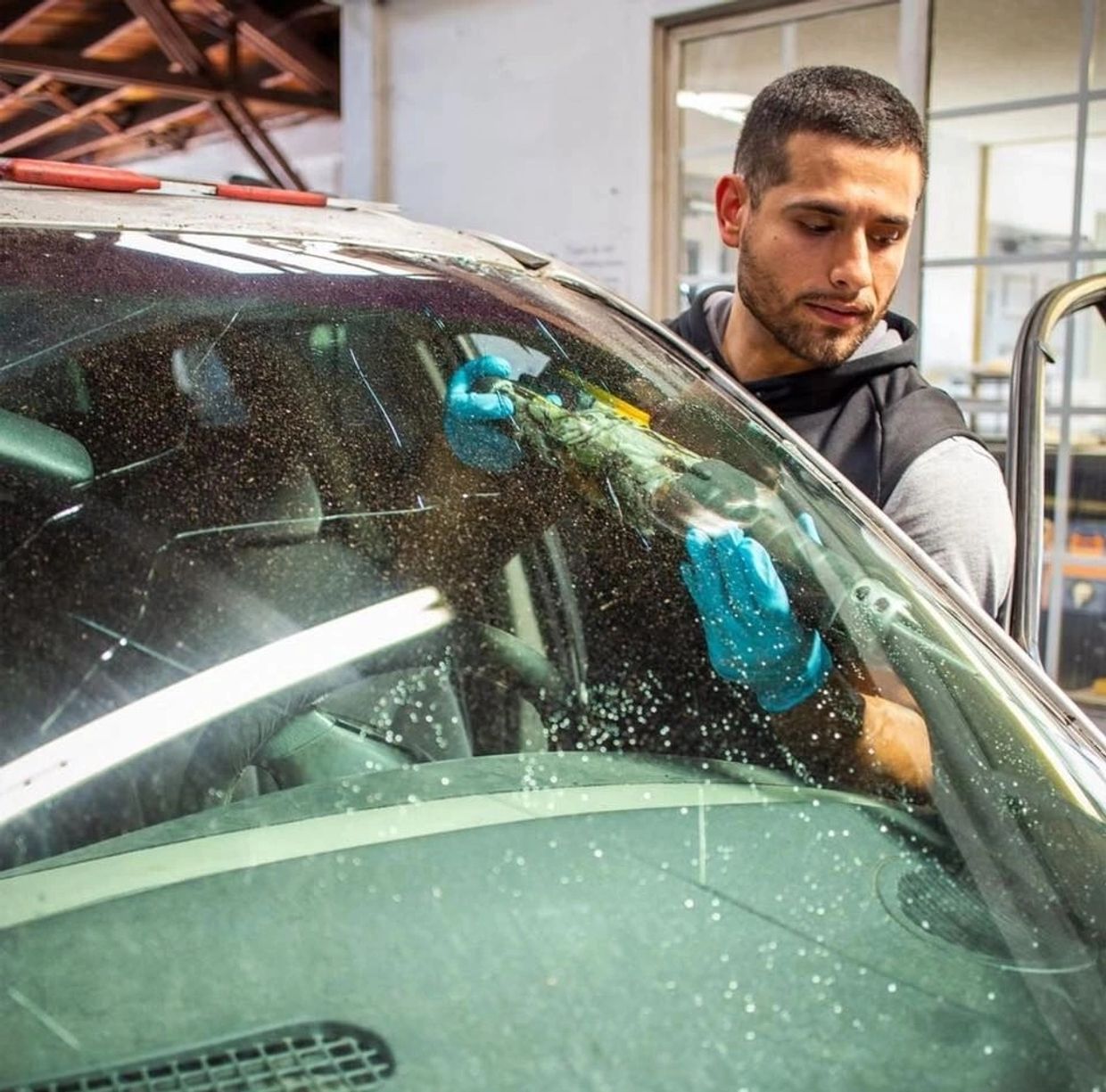 Auto glass installer replacing a front windshield.